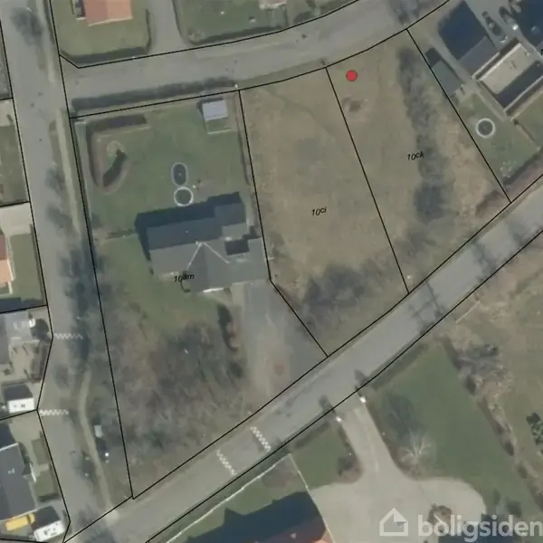 Bygning set fra oven på en grund markeret med sorte linjer. Grønne arealer omgiver bygningen. Veje og yderligere parceller ses i nærheden. Tekst: "10 m", "10 ck", "Boligsiden".