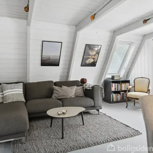 Køkken med hvide skabe og stålbordplade, åbne hylder med service, åbent mod en terrasse. En stor glasdør og et vindue giver udsigt til en have med træer i baggrunden.