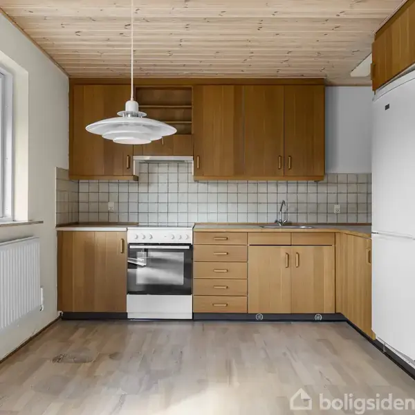 Køkken med lyse træskabe og hvidevarer. Komfur står centralt, omgivet af skabe. En enkel, hvid lampe hænger over spisepladsen. Flisebelægning som backsplash, vindue til venstre, lyse trægulve.