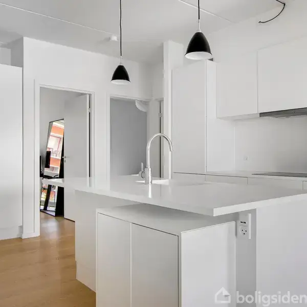 En stue med en blå sofa og lænestol står ved et lille sofabord. Et tv hænger på væggen. En åbning fører til en altan med to stole.
