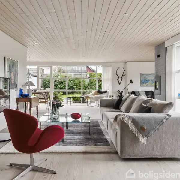 Et rum med vinreol fyldt med flasker, en stor vintønde i midten, og en trappe til en kælder. Væggene har dekorationer og plaketter.