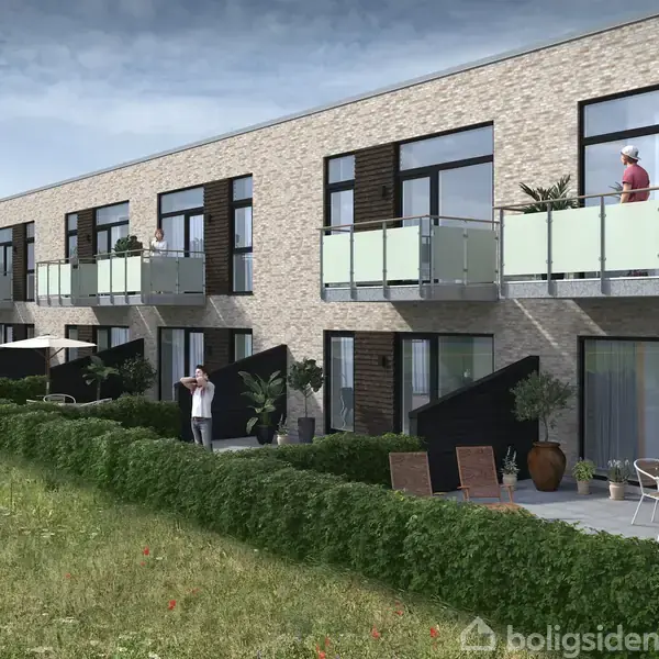 Rækkehuse i moderne stil står på række. Personer sidder og står udenfor, nogle på balkoner, andre i en have med græs og buske. Himmel delvist overskyet i baggrunden.