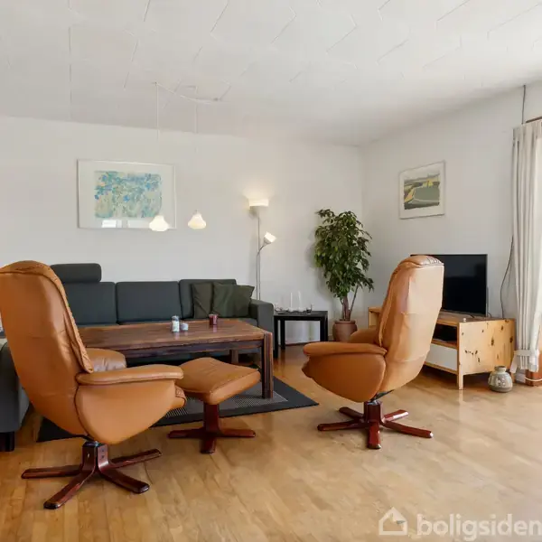 Brune læderstole står foran et sofabord i en stue med trægulv. En grå sofa er i baggrunden, mens lamper og malerier pryder de hvide vægge.