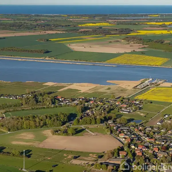 Landsby med huse omgivet af marker, som ligger ved en bred flod. Floden skærer gennem det flade landskab, hvor store gule og grønne marker dominerer udsigten i det fjerne.