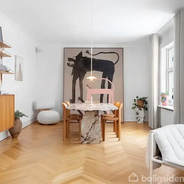 To toetages rækkehuse med rødt tegltag står side om side i et snedækket bykvarter. Den venstre bygning er rosa, den højre hvid. En sort bil holder parkeret foran.