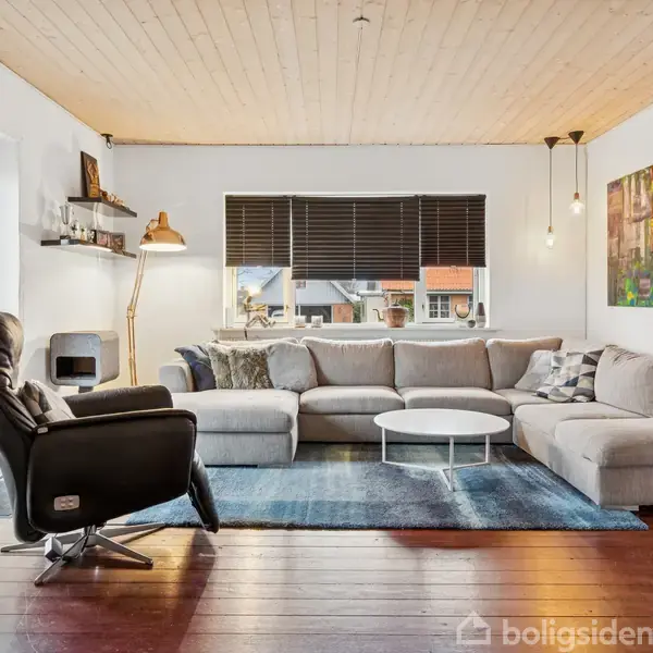 Hvidt badeværelsesskab med spejl, omgivet af hvide fliser. To blå kurve og en rød krukke står på hylderne. To håndklæder hænger på væggen.