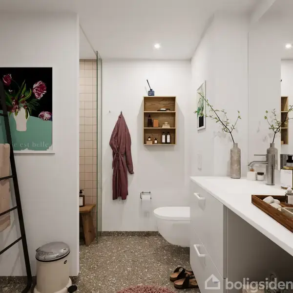 Et badeværelse med moderne indretning. En rosa badekåbe hænger på væggen. Der er hylder med toiletartikler, en plante i en vase, og et toilet. Billedet viser et hyggeligt miljø.