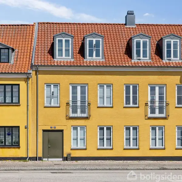 Gult rækkehus med rødt tegltag og hvide vinduer. Hoveddør med nr. 40. Står i bymiljø med fortov og vej foran.