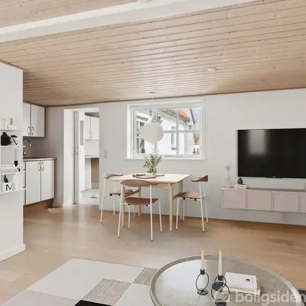 Et moderne køkken med hvide skabe og stålgreb. Køkkenet har indbygget ovn, kogeplade og en vask. Der er en lille opvaskemaskine og køleskab. Det ligger i et lyst rum med trægulv.