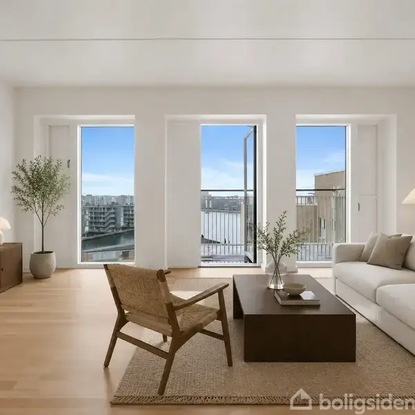 Stue med sofa, stol og tv, hvor en stor glasdør åbner ud til en balkon. Moderne indretning med lyse farver, lamper, planter og udsigt over en by.