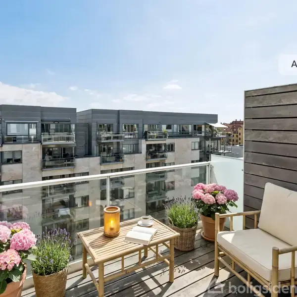 En balkon med træstole og et bord, omringet af blomster i potter. Bygninger ses i baggrunden under en klar blå himmel. Tekst: "AI visualisering".