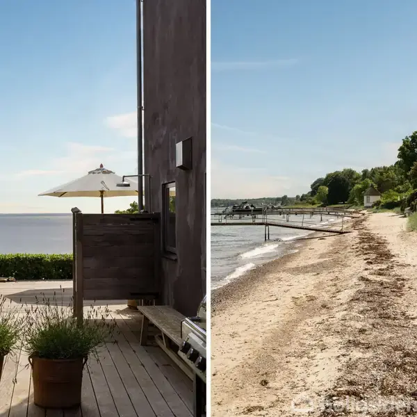 Terrasse med planter i krukker ved siden af et hus, med en parasol i baggrunden, der vender ud mod havet. Ved siden af ses en sandstrand med græs og træer.