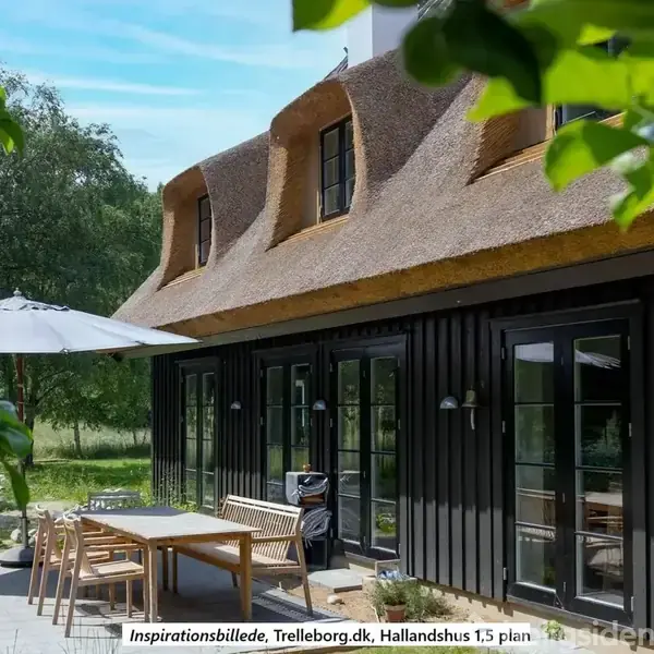 Stråtækt hus med sorte trævægge har en terrasse med et bord, stole og parasol. Omgivet af frodig natur. Tekst: "Inspirationsbillede, Trelleborg.dk, Hallandshus 1,5 plan".