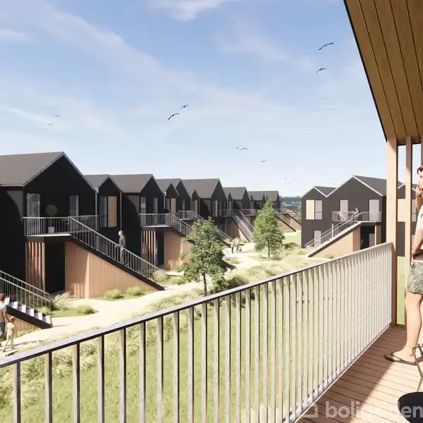 En person står på en balkon og kigger ud over en række moderne, sorte rækkehuse med trædetaljer omgivet af grønne områder og trapper. Fugle flyver på himlen.