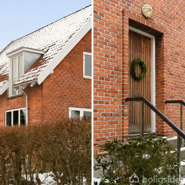 Rødt murstenshus med sne på taget. Til venstre ses gavle med kviste, til højre en dør med krans. Omgivet af buske og sneklædt jord.