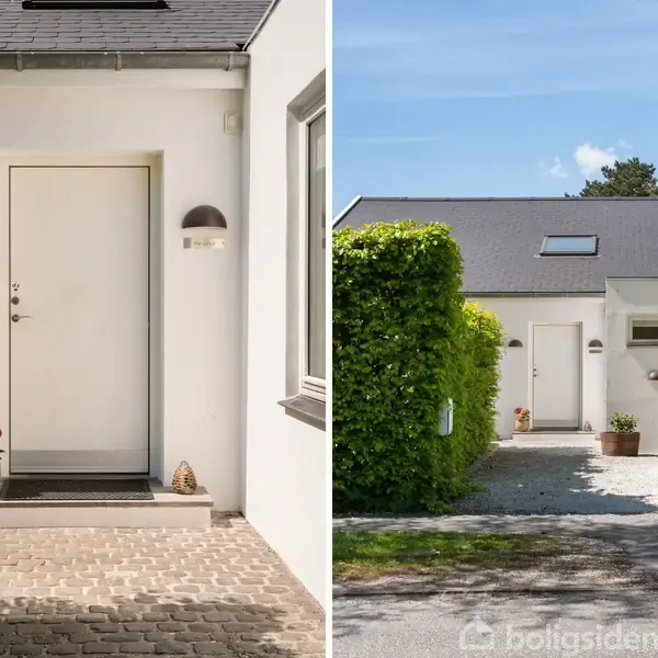 En moderne hvid bygning med en enkel indgang dekoreret med blomsterkrukker. Den brede indkørsel er flankeret af grønne buske under en klar blå himmel.