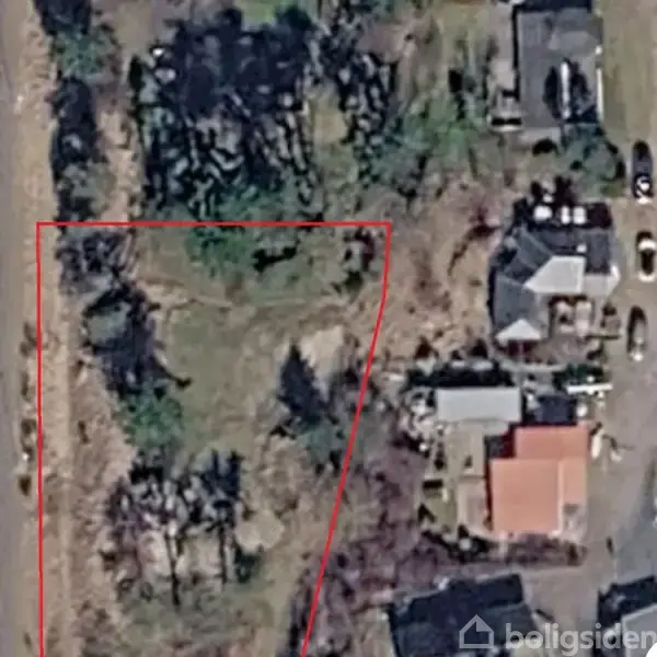 Grund inden for en rød markering beliggende ved siden af flere huse og veje. Området er omgivet af træer og buske.