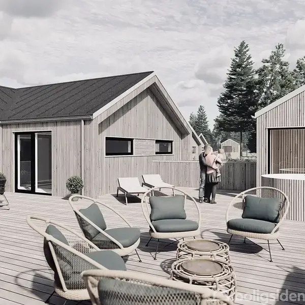 Træhus med stor terrasse, hvor stole og borde er arrangeret i grupper. En person står ved et hegn. Omkring er der skov og himmel med lette skyer.