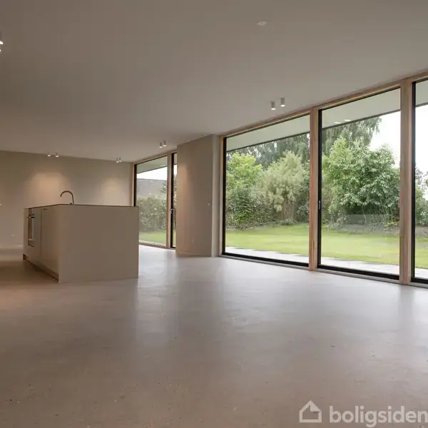 Bygning med moderne design, har mørke træpaneler og store glasdøre. Taget er skråt med rene linjer. Omgivet af en græsplæne og grønne buske i en have.