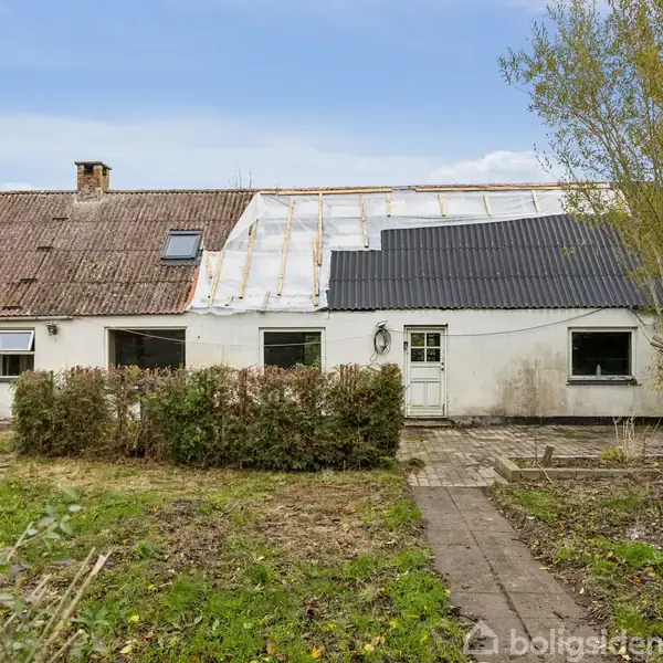 Et traditionelt hvidt hus med skrånende tag er omgivet af en græsplæne og en brostenssti, som fører til hoveddøren. En træ står på højre side.