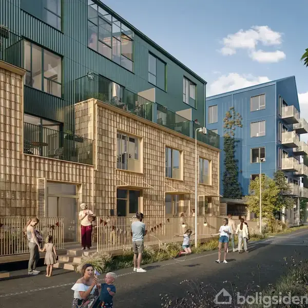 En række moderne lejlighedsbygninger med lokkende facader ses i et boligområde på en solrig dag. Mennesker går eller står omkring bygningerne, der er omgivet af træer og græsarealer.