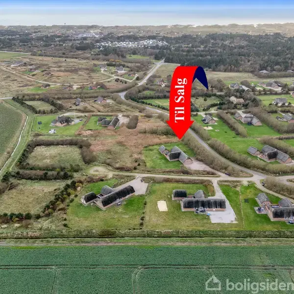 En rød pil med teksten "Til Salg" peger ned mod en ejendom beliggende i et grønligt, landligt område med spredte huse og marker.