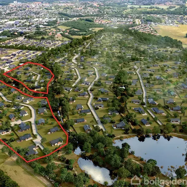 Nabolag vist oppefra omfatter flere huse, omkranset af træer og veje i et grønt landskabsområde. Rødt omrids markerer en del af området. Tekst: "Udbygning af det markerede område og grunden udstykkes nu".