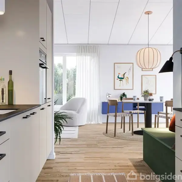 Køkken med hvide skabe til venstre, lamper og planter. I baggrunden en stue med spisebord, stole og sofa nær et stort vindue. Vægkunst og lyse trælofter.