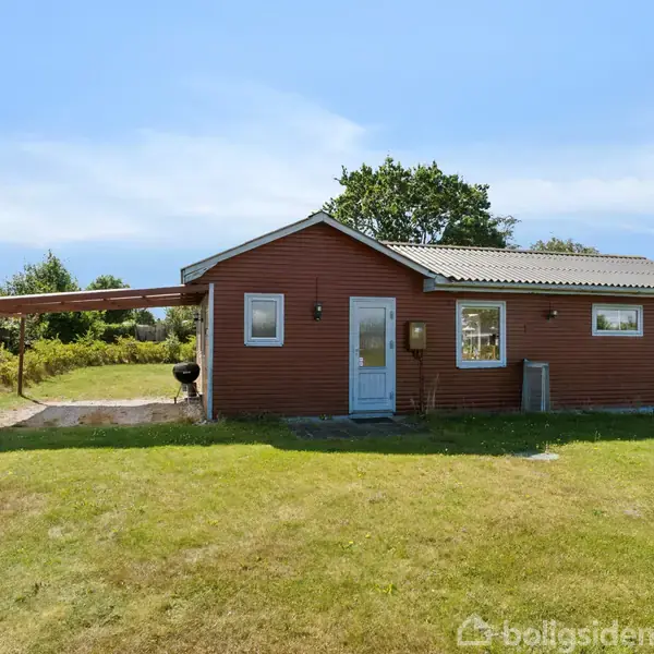 Rødt hus med gråt tag står stille i en grøn have. Ved siden er en overdækket terrasse, omgivet af træer og hegn.