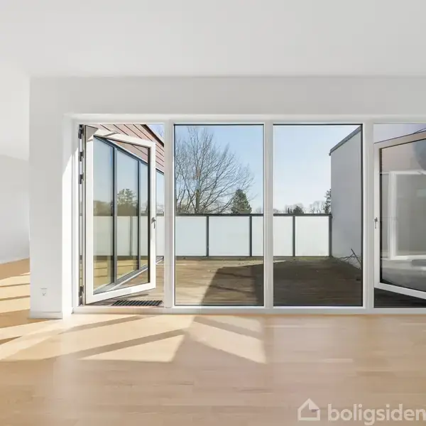 Glasdøre åbner mod en rummelig terrasse, hvor man kan se træer i baggrunden. Lys trægulv dominerer rummet, mens sollys strømmer ind og kaster skygger.