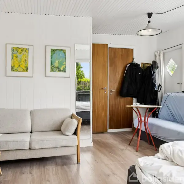 Badeværelse med toilet og håndvask. Bruseren er til venstre ved et lille vindue. Rummet er hvidt med fliser og en bruseforhæng. Intet synligt tekst.