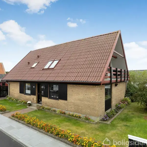 Et to-etagers murstenshus med rødbrunt tegltag og store vinduer står i et velplejet forstadskvarter. Huset har en lille have med blomsterbede, og en indkørsel til venstre.