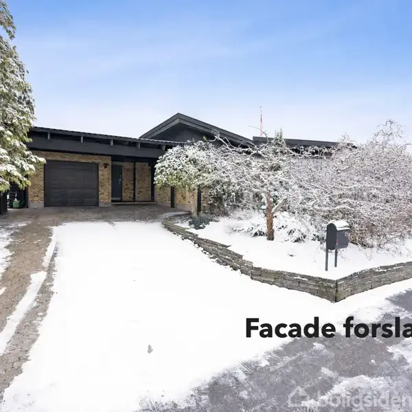 Et moderne hus med mørk facade står i et snedækket landskab. Der er en indkørsel til venstre og sneklædte træer omkring. Tekst: "Facade forslag".