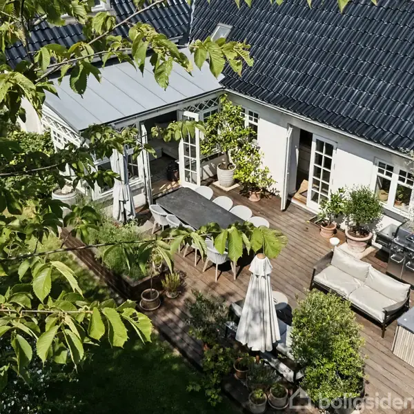 Entré med lys beige vægge fremviser et tæppe i rød tone på gulvet. Der er en bænk ved siden af en lukket dør. Trappe ses i baggrunden.