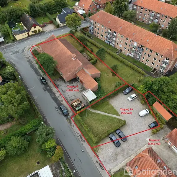 Bygning omgivet af græsarealer og parkeringsplads, set fra oven. Røde grænser markerer forskellige områder: 1.124 m², Tingvej 2A 502 m², Tingvej 2 1.154 m². Området er i et beboelseskvarter.