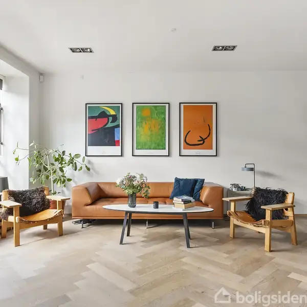 En lys stue med en brun sofa centreret mod en hvid væg, flankeret af to stole. Tre farverige kunstværker hænger over sofaen. Store vinduer og planter omkranser rummet.