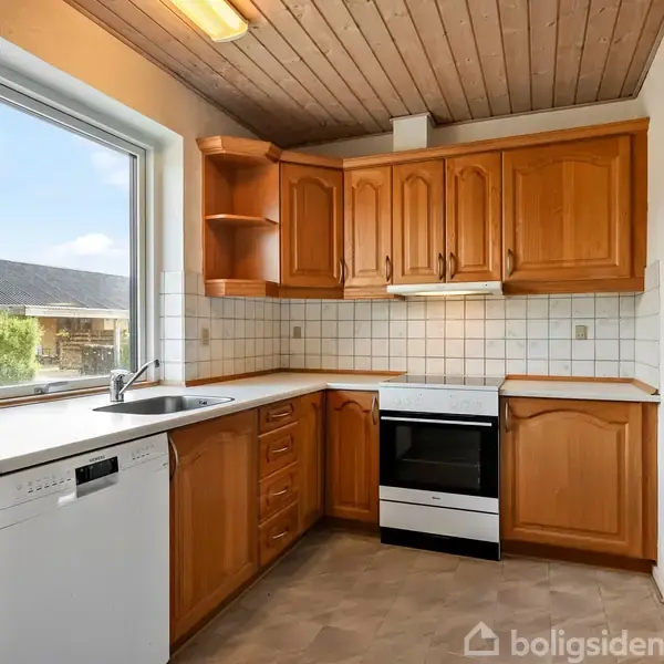 Køkken med træskabe og en hvid ovn. En stor vindue lader naturligt lys ind. Fliser på væggen over køkkenbordet. Opvaskemaskine ved siden af vasken.