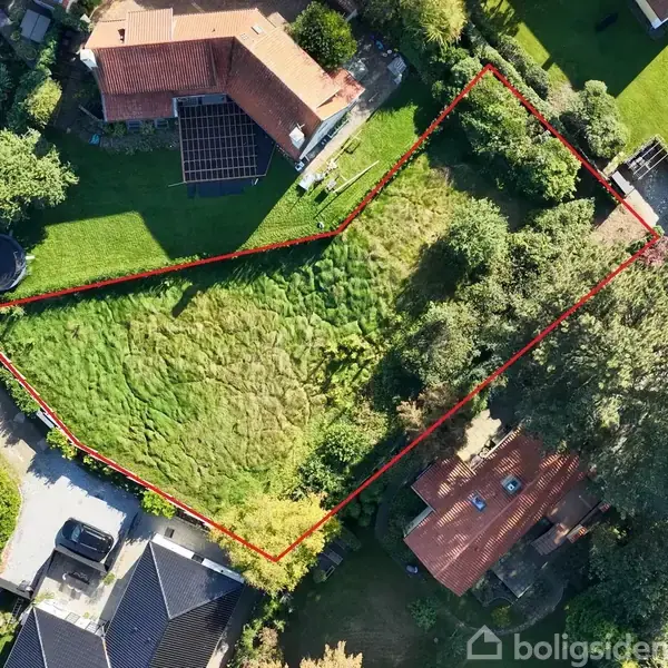 Grunden er afgrænset med en rød linje, omgivet af grønne områder og huse i en villakvarter.