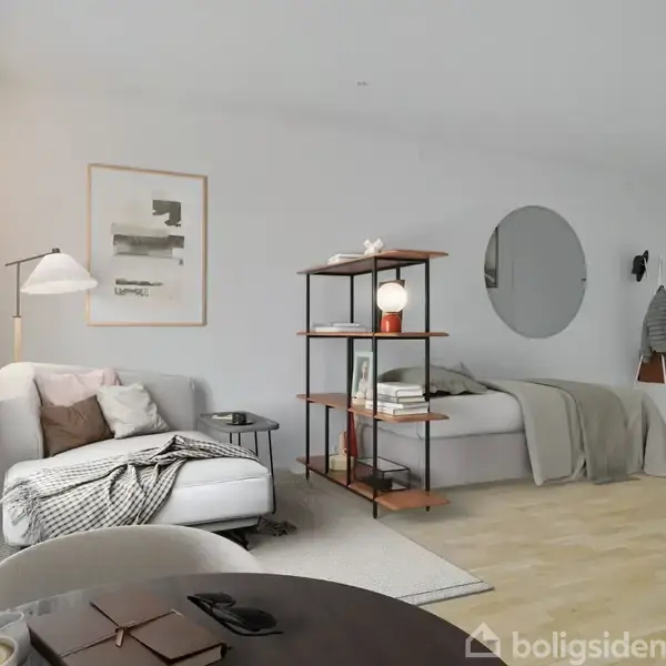 Stue med en sofa og en læselampe ved siden af, en reol fyldt med bøger og dekorationer. I baggrunden ses en seng med et rundt spejl på væggen.