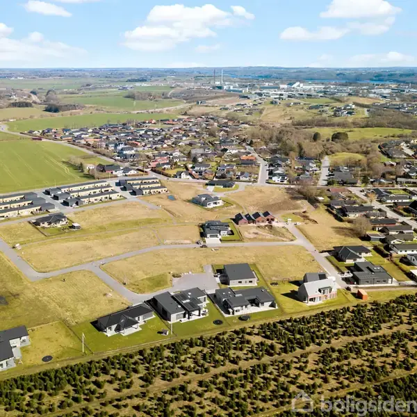 Bebyggelse af huse; bosat i et kuperet boligområde; omgivet af marker, veje og små nabolag, set fra luften.