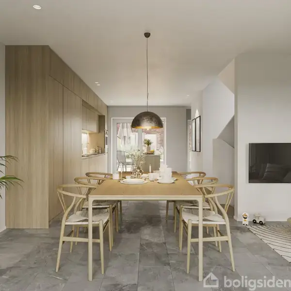 En spisestue med et træbord og seks stole, belyst af en hængelampe. Til venstre ses indbyggede skabe, og til højre en stue med sofa og vægmonteret tv.