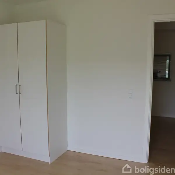 Trappe fører opad mellem to murstensbygninger i en overdækket gård med flisebelagt gulv. Trapperne er i metal med rækværk, og murene har vinduer og døre.