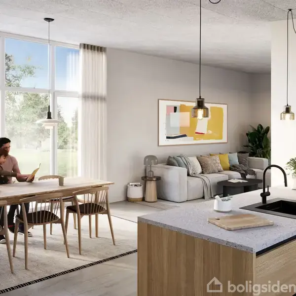 En moderne stue-køkken med åben plan. En person sidder ved spisebordet og læser, mens vinduer bagved viser natur. En sofa med puder og kunst på væggen kompletterer rummet.