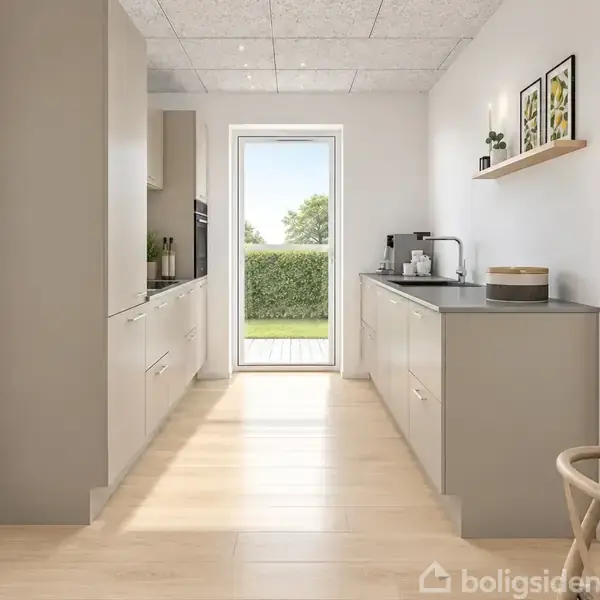 Et køkken med beige skabe langs begge sider af rummet, en dør fører ud til en solrig have. Lys trælaminatgulv, hylder med planter og billeder på væggen.