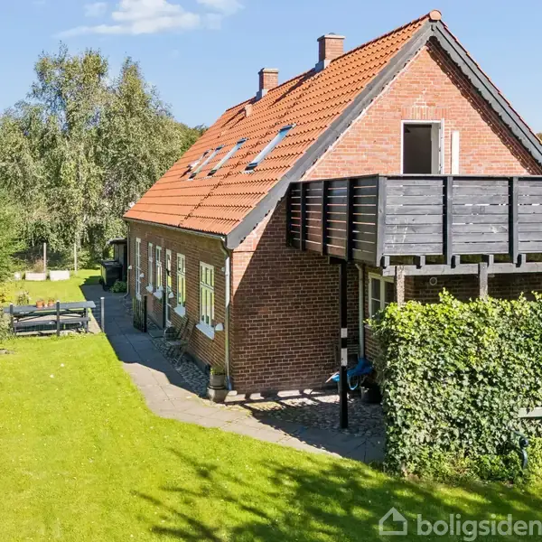 Hvid dør med glasruder står åben mod en gang. Et træskab står til højre for døren. Tekst på væggen: "Home is my happy place". Trægulv og hvidmalede vægge.