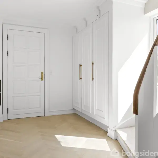 En lys entré med en hvid dør til venstre, indbyggede garderobeskabe langs væggen, en lampe på en hylde, og en trappe med trærækværk fører til øverste etage.
