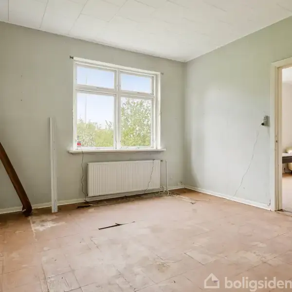 Et tomt rum med et afskallet gulv. Et vindue lukker naturligt lys ind. Rummet er forbundet til en anden stue med et bord og stole. Ingen tekst til stede.