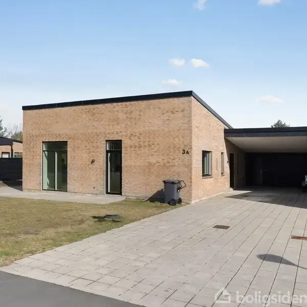 En moderne, rektangulær murstensvilla står til salg ved vejen. En indkørsel fører til en carport med en bil. Skiltet ved postkassen siger "TIL SALG" med tekst "home" og "Boligtilsalg.dk".