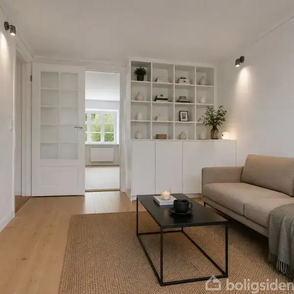 Stue med beige sofa og sofabord, fladskærms-TV monteret på venstre væg. Hylder med dekorationer i baggrunden. Plakat med teksten "NATURSK" på højre væg. Skydedøre, lyse træpaneler.