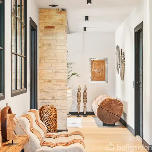 En gang viser dekorative træudskæringer placeret langs væggene. Der er en bjælke som bord og kunstværker på væggene. Rummet er lyst med murstensvæg og sorte vinduesrammer.